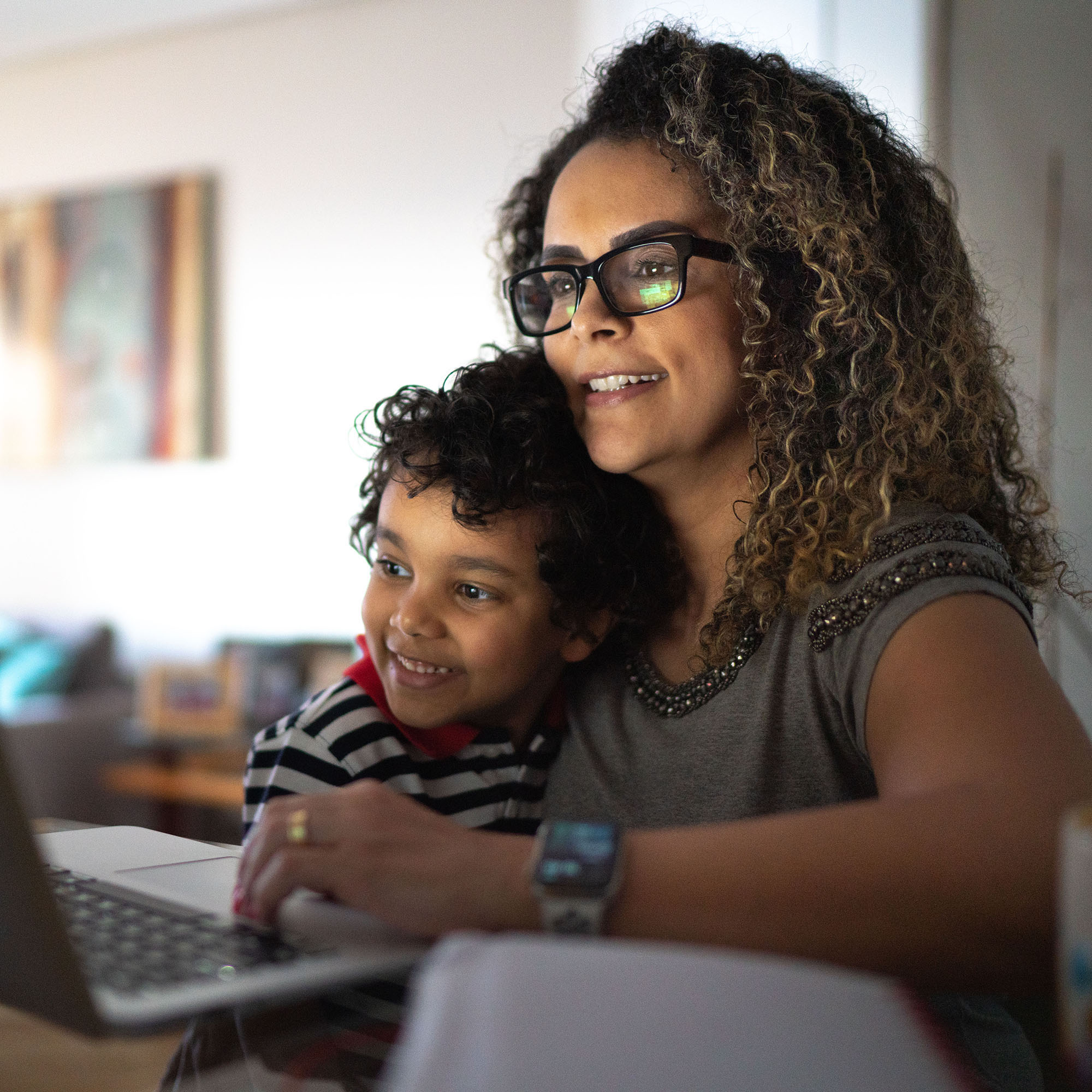 Mature woman working at home, carrying young son - stock photo. © Getty Images