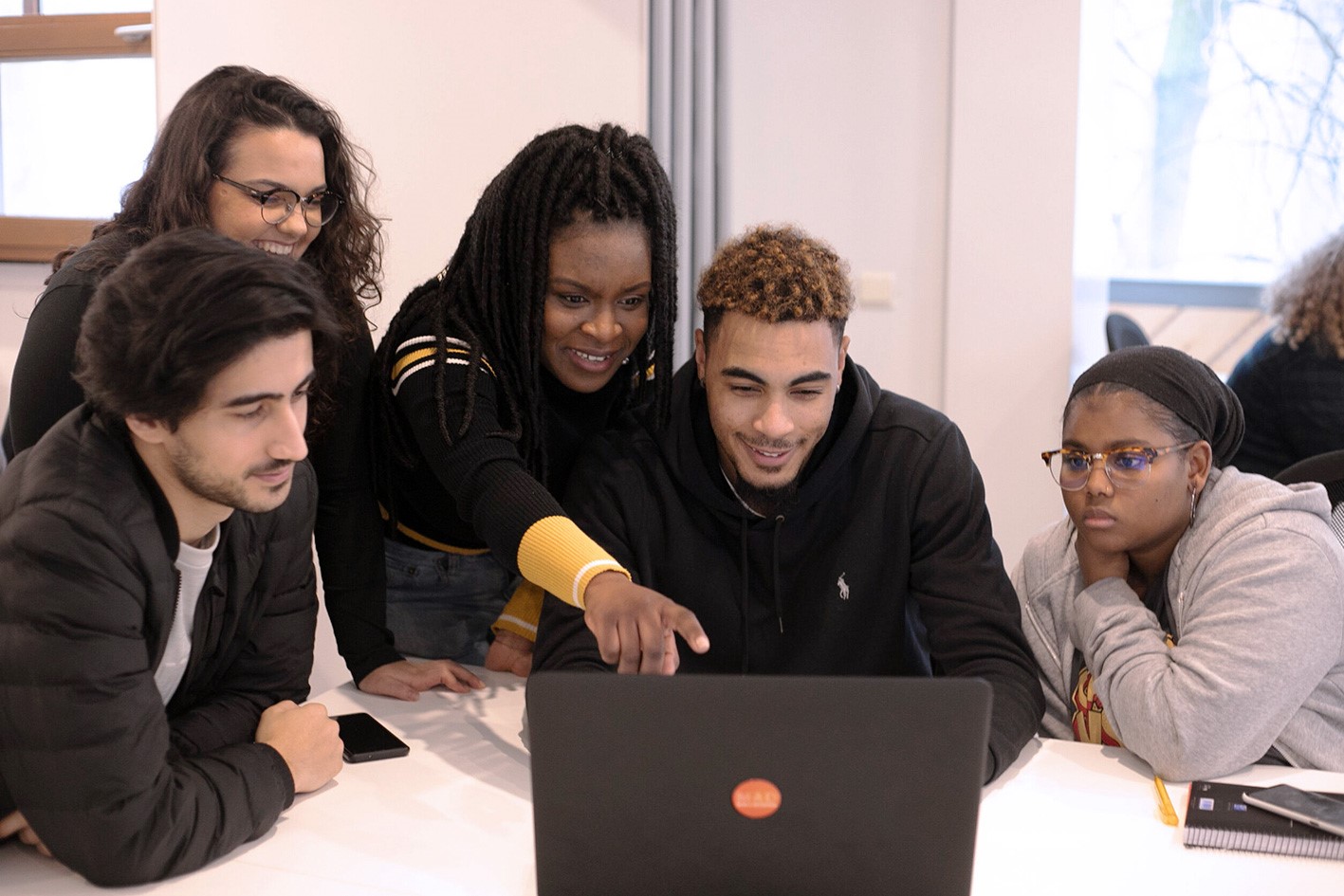 A group of people looking at a laptop screen together